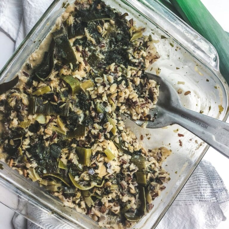 A casserole dish filled with leek, kale, and chicken.