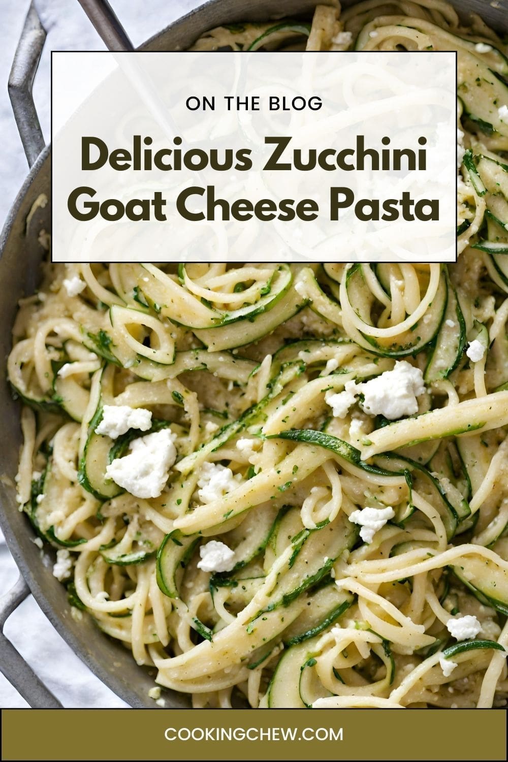 A skillet filled with cooked pasta with zucchini ribbons, creamy goat cheese.