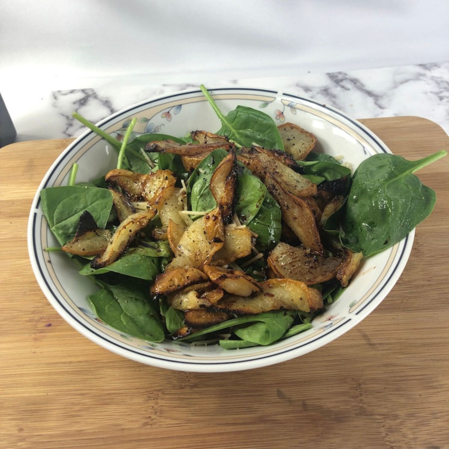 A close-up of a pear salad with balsamic drizzle and fresh greens