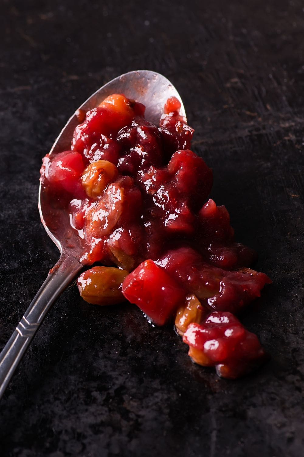 A spoonful of cranberry pear sauce on a black background.
