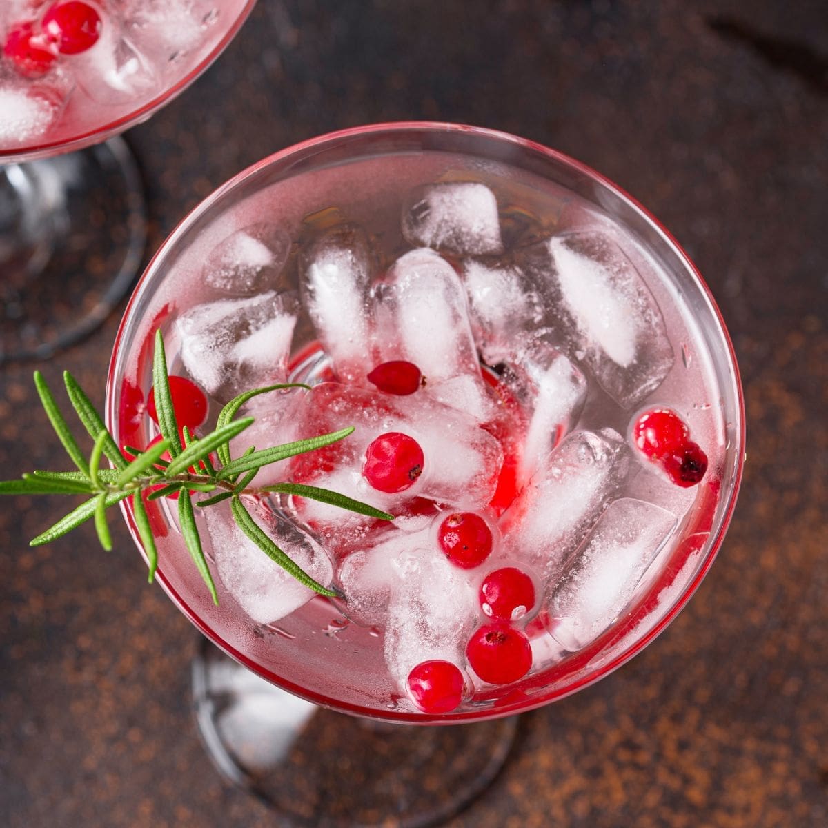 The image shows a glass filled with a cranberry margarita garnished with fresh cranberries.