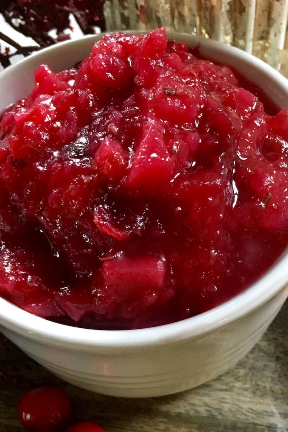 The image shows a bowl of cranberry pear sauce on a wooden table.