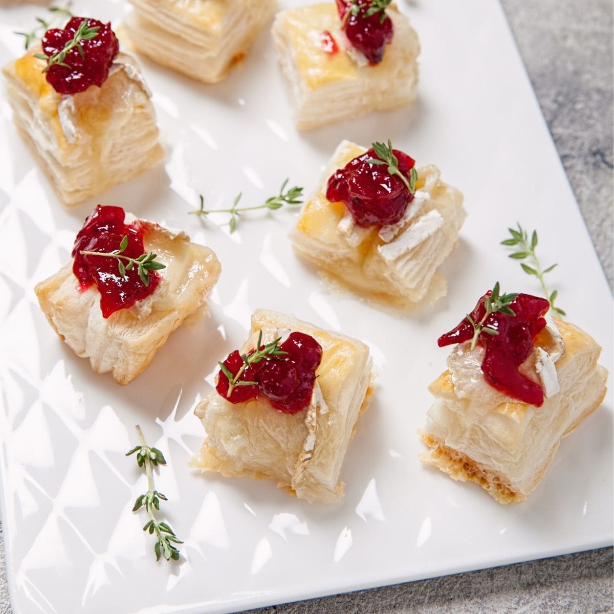 A close-up of a white plate topped with puff pastry and cranberry sauce.