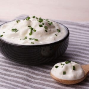 Sour Cream in a wooden bowl with chives sprinkled on top