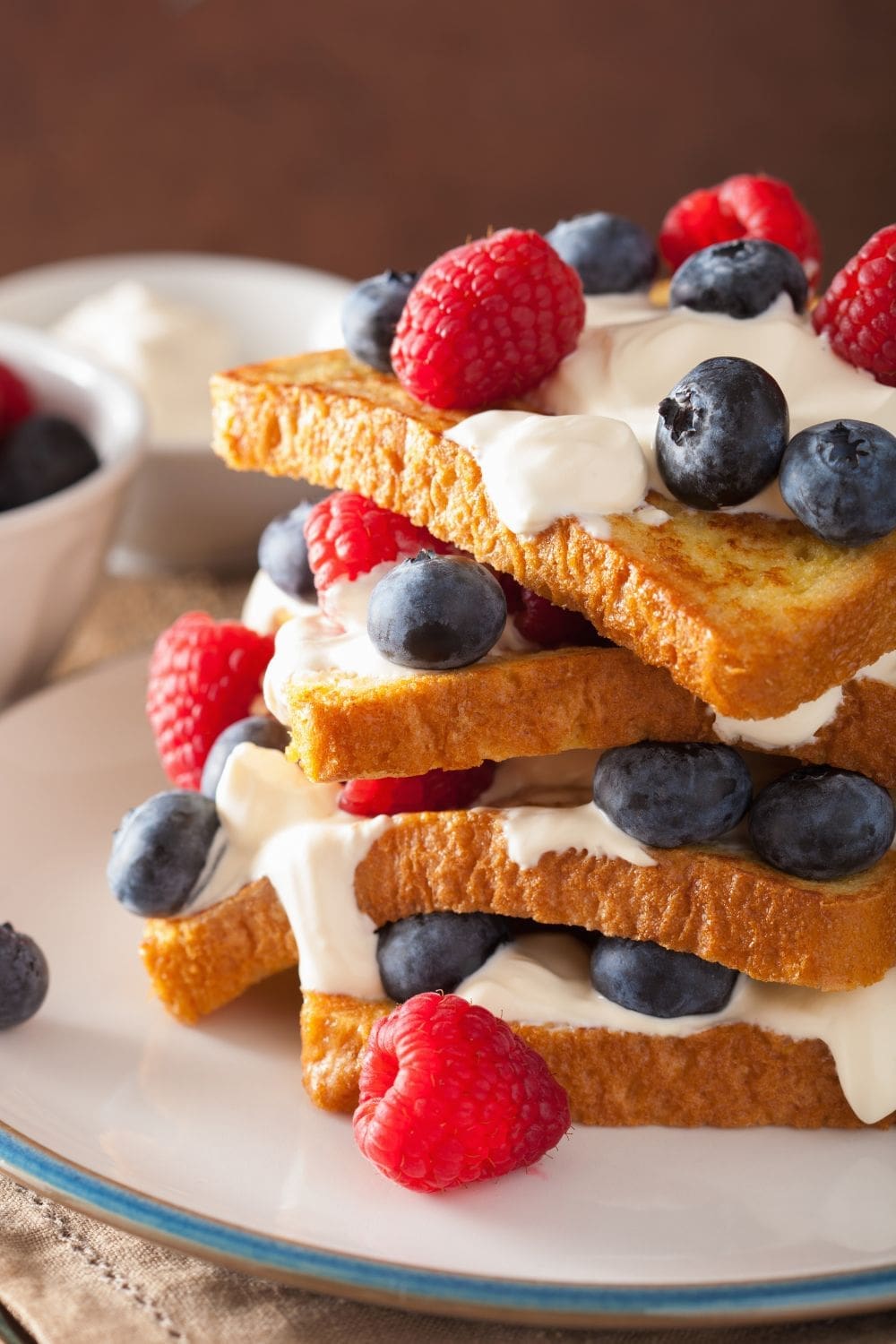 A stack of French toast topped with blueberries, raspberries, and creme fraiche