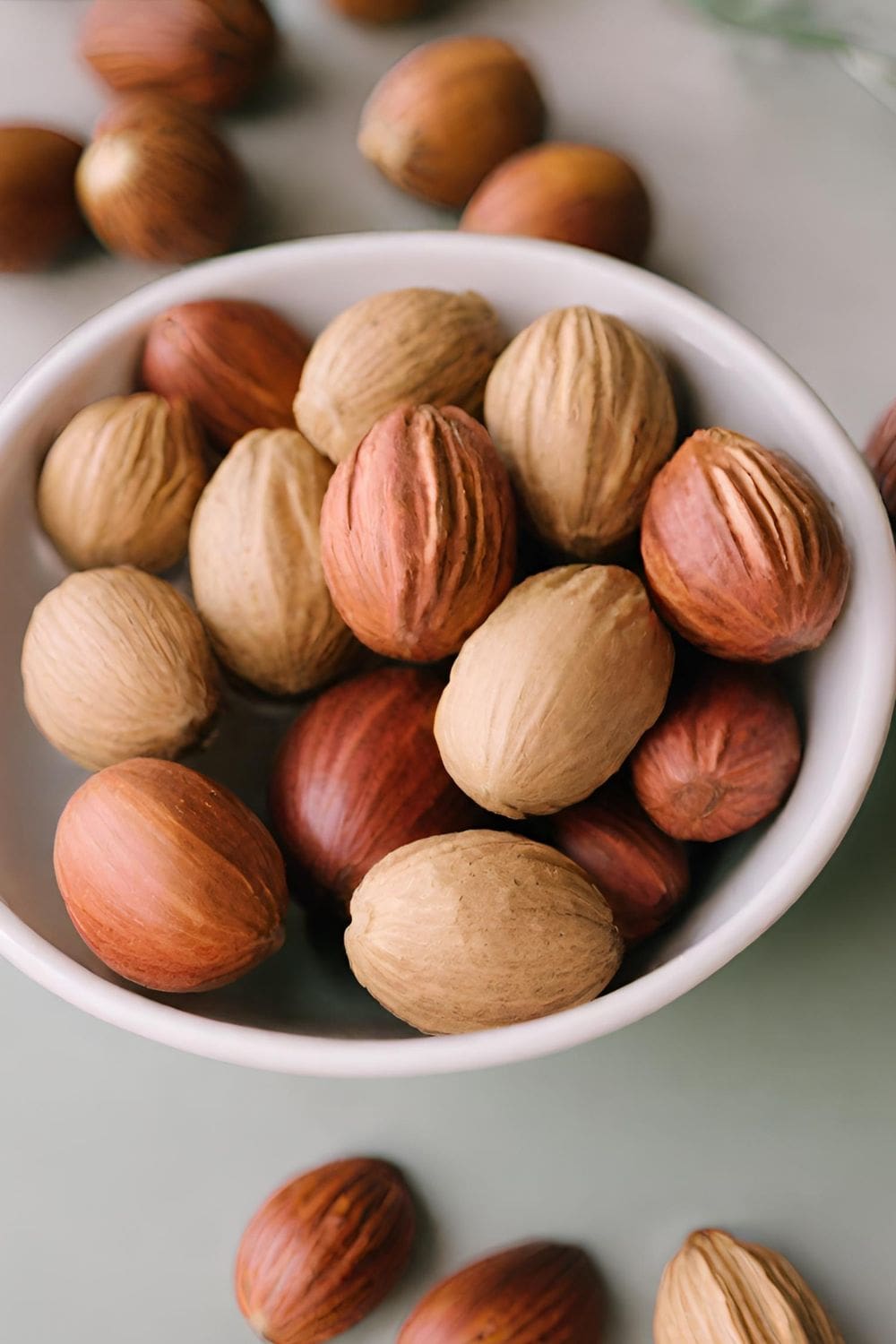A bowl of nutmeg sits on a wooden table.