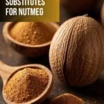 A wooden spoon filled with nutmeg powder next to a whole nutmeg nut on a wooden table.