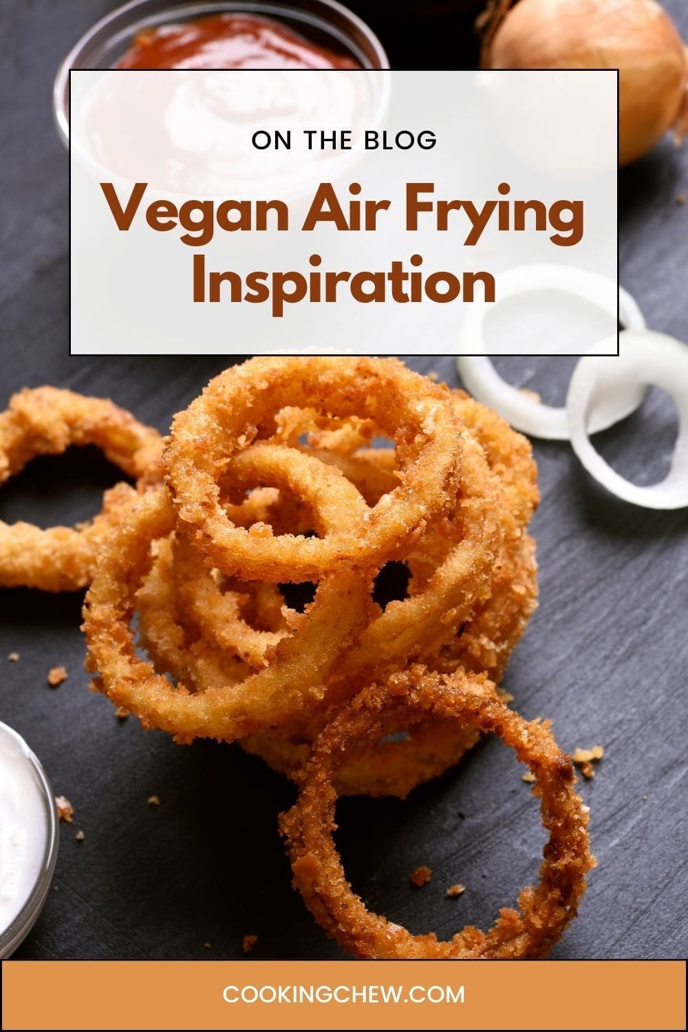A plate of golden onion rings piled high on a light wooden table. 