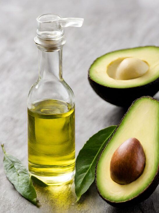 A bottle of avocado oil next to an avocado. 