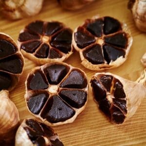 Black garlic cloves cut in half on a wood cutting board