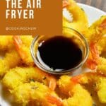 A close-up of golden air-fried butterfly shrimp, with the shrimp’s crispy, flaky breading visible.