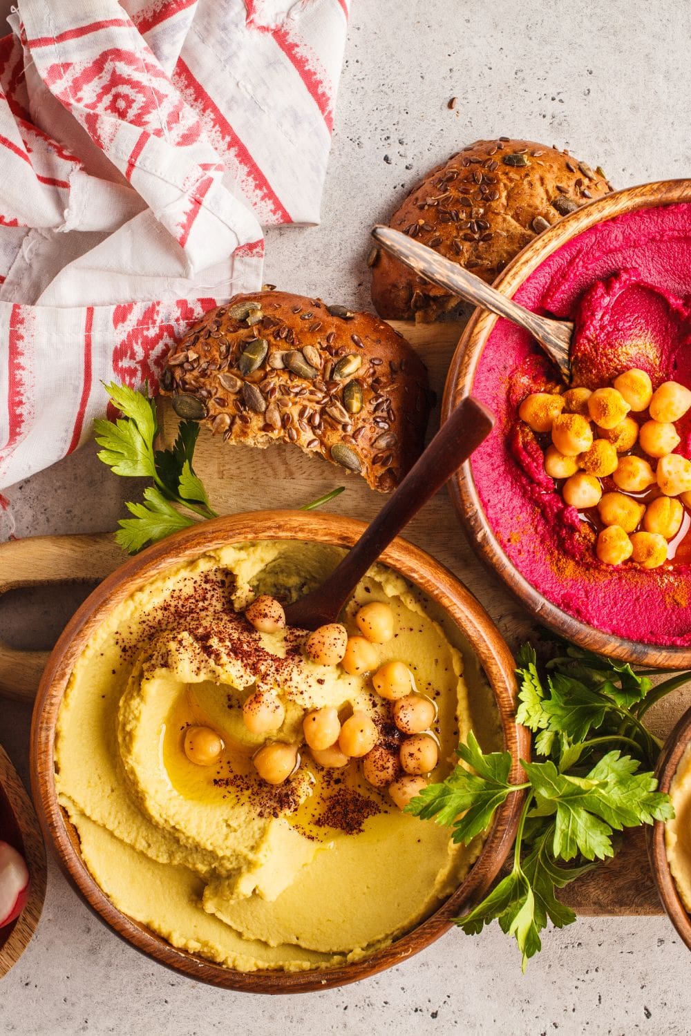 Two bowls of hummus on a cutting board.