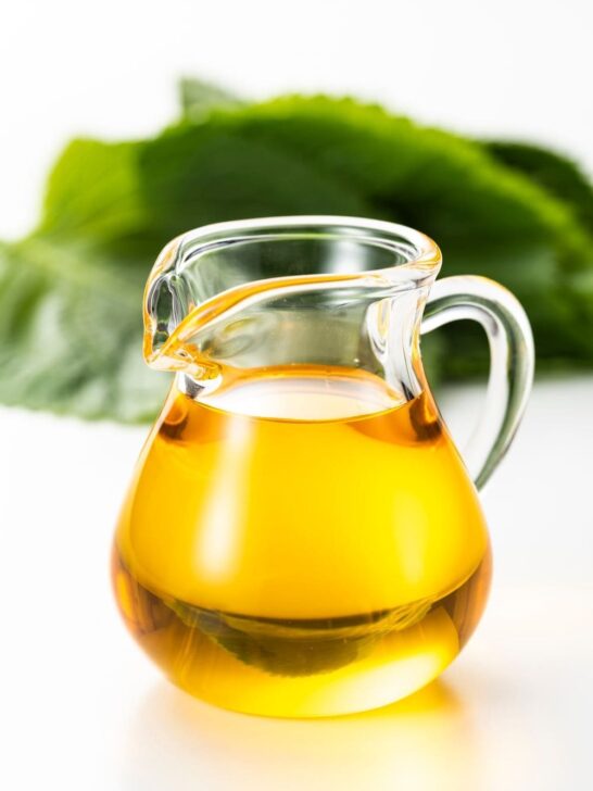 A clear pitcher of perilla oil on a white table.