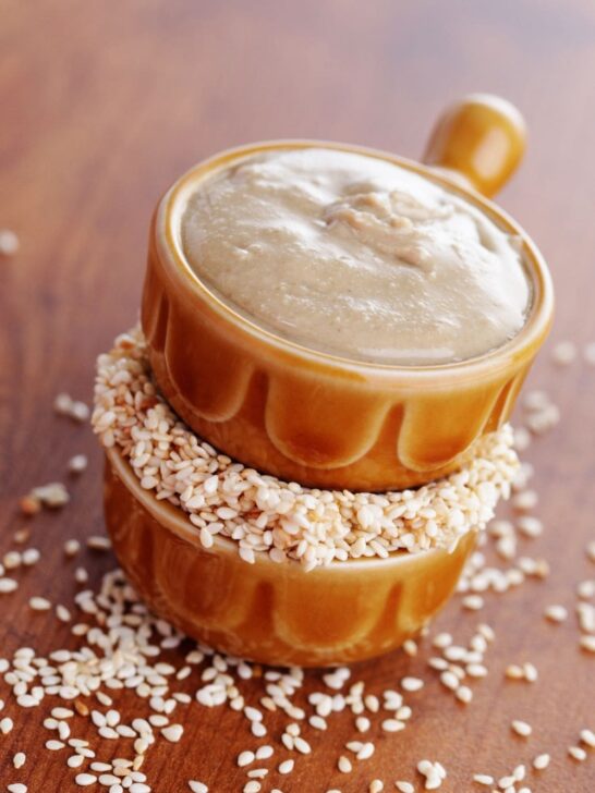 A close-up of a bowl of tahini on a wooden table.