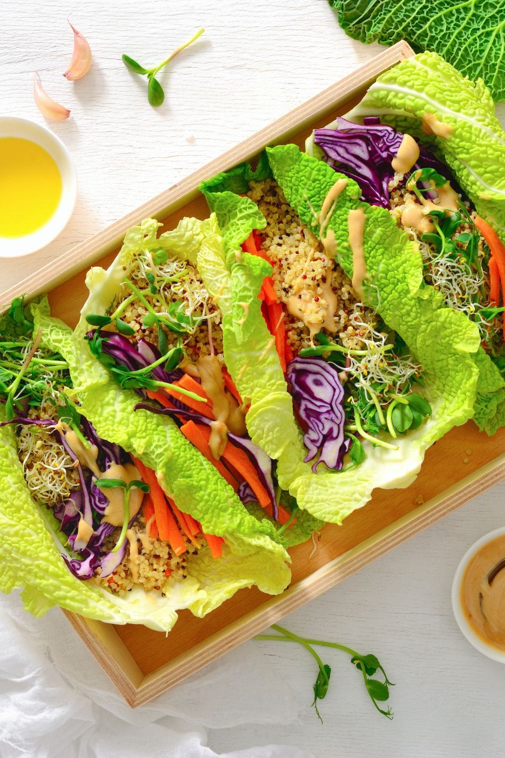 A wooden tray filled with lettuce wraps topped with various vegetables.