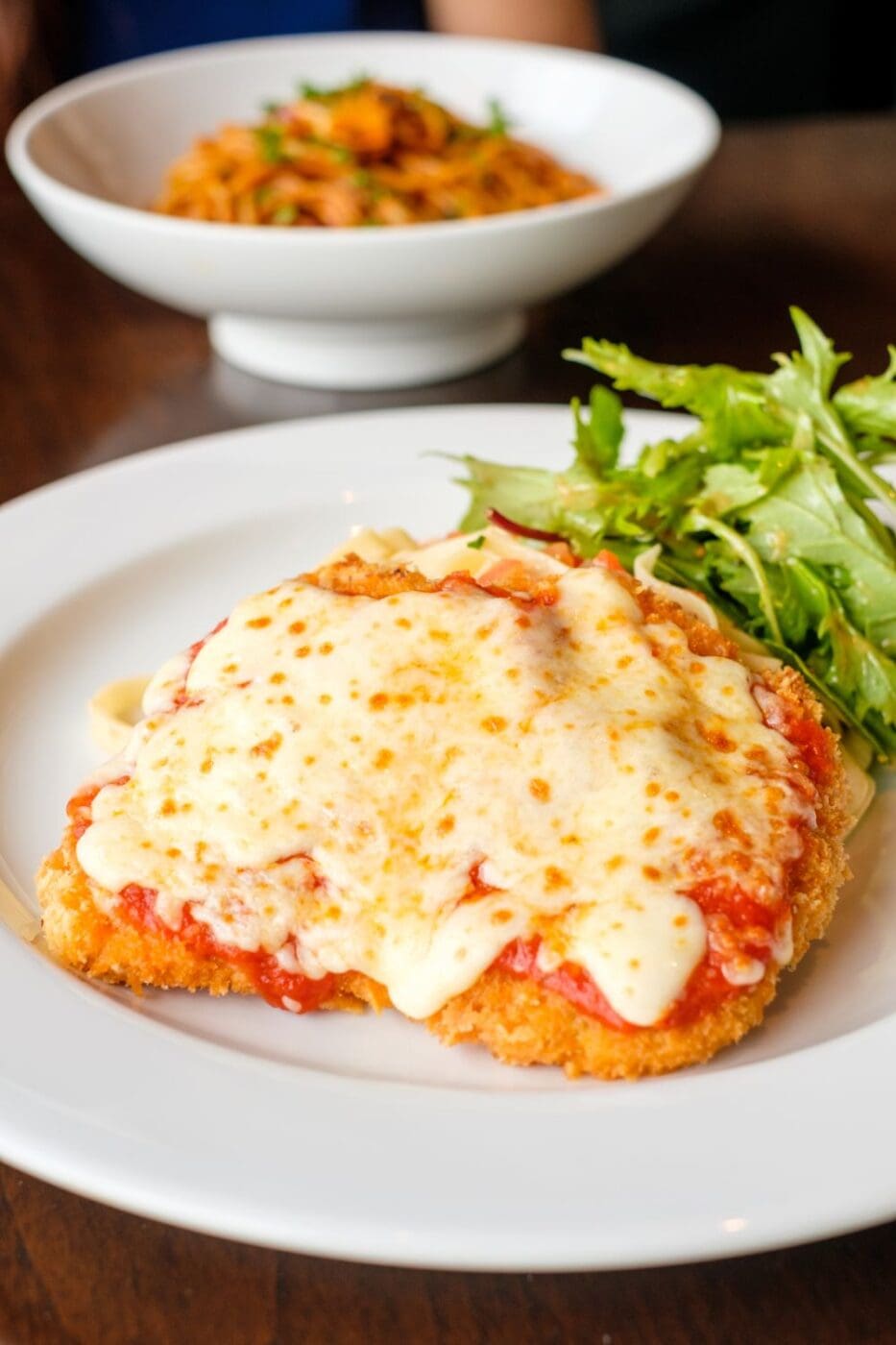 A plate of chicken parmesan with tomato sauce and mozzarella cheese.