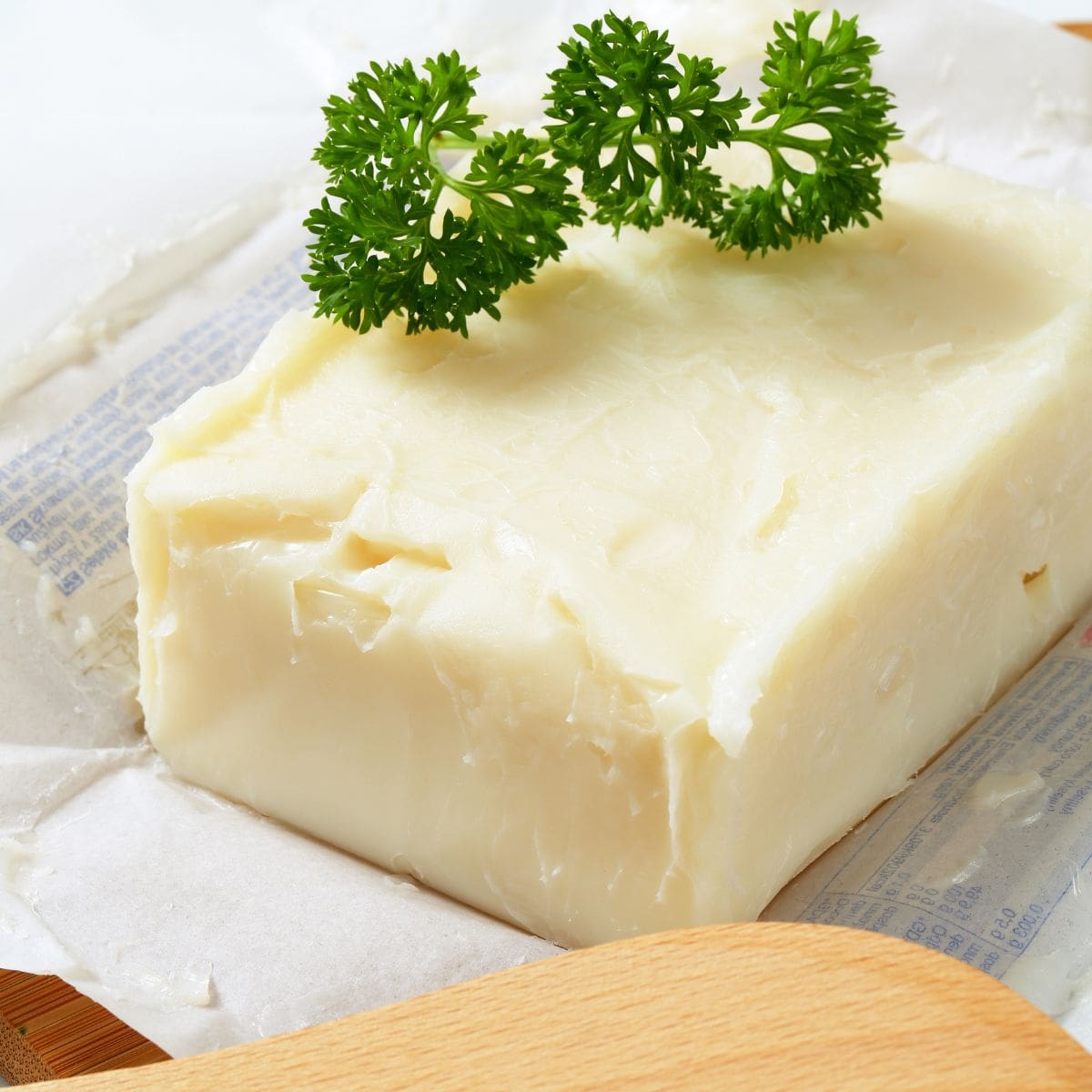 A close-up photo of a rectangular block of lard with two green parsley leaves on top.