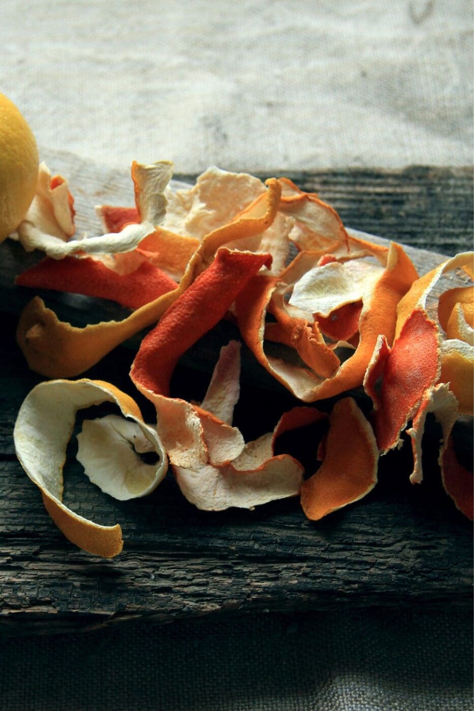 A pile of orange peel on a wooden cutting board.