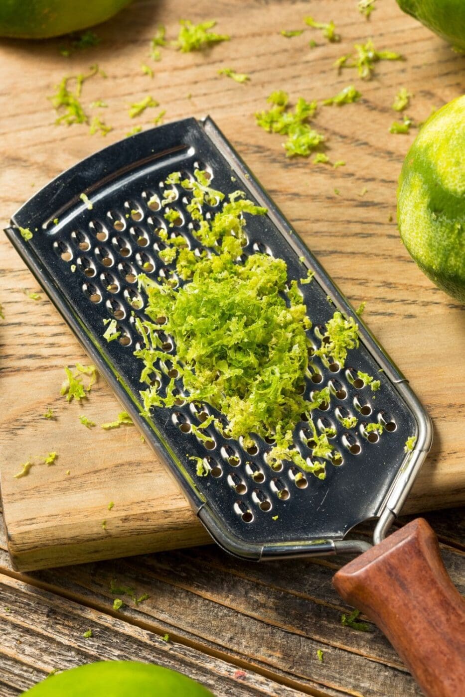 Lime zest on a grater on a cutting board.