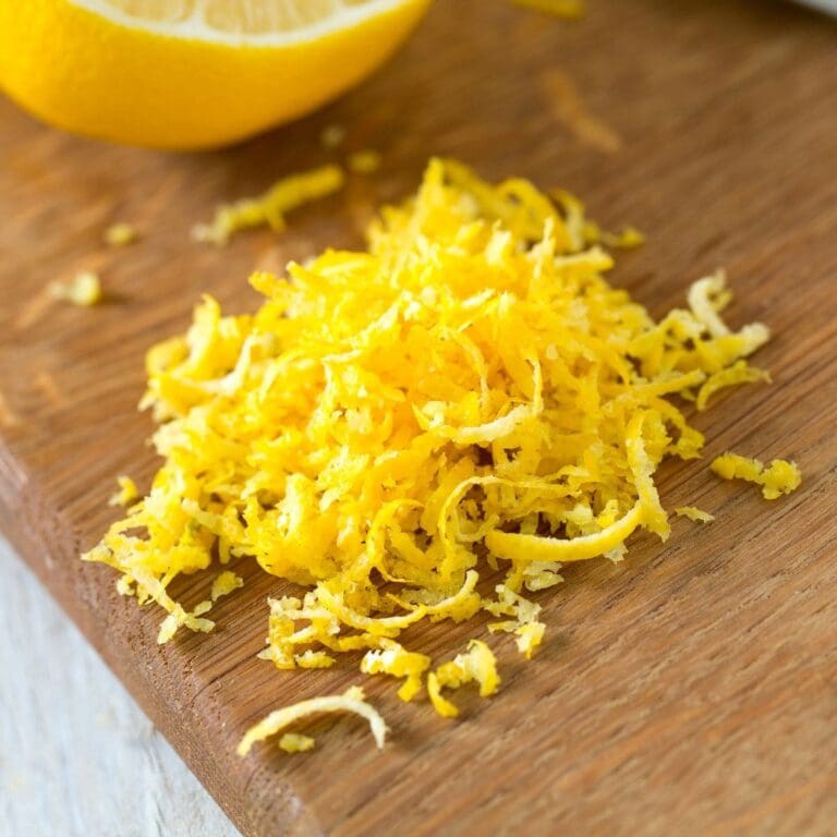 A pile of grated lemon zest on a wooden cutting board.