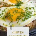 A sunny-side up fried egg in a cast iron skillet with chopped chives sprinkled on top.