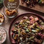 A plate of corned beef and Brussels sprouts on a wooden table.