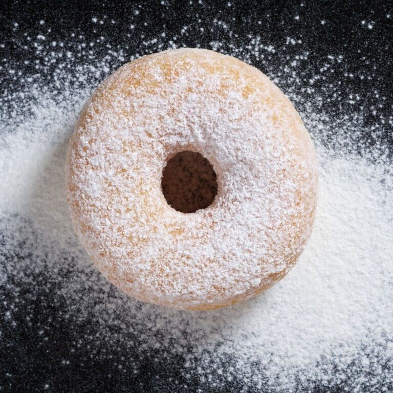 A close-up view of a delicious donut, its surface blanketed in a fine layer of powdered sugar.