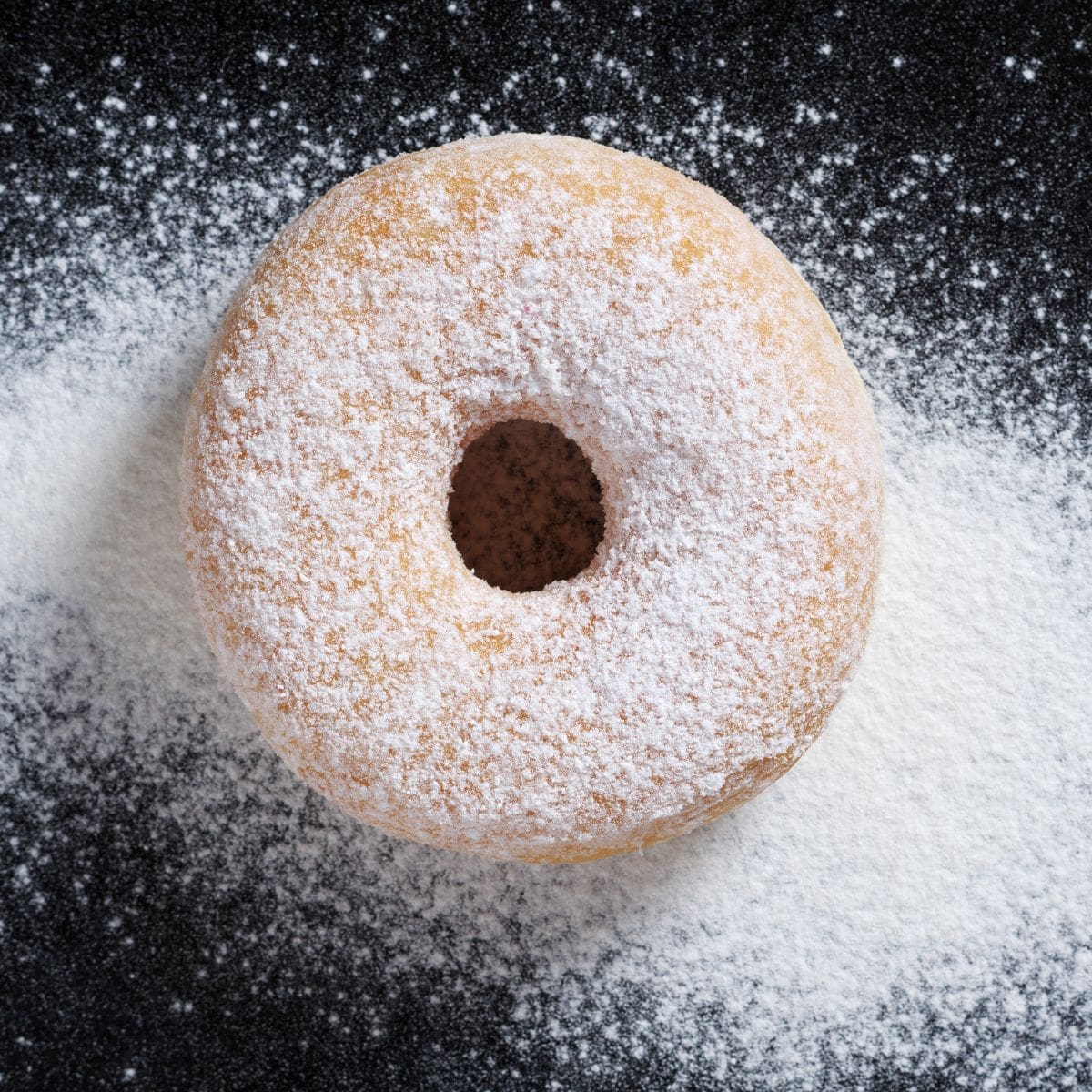 A close-up view of a delicious donut, its surface blanketed in a fine layer of powdered sugar.