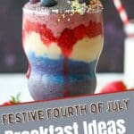 A red, white, and blue smoothie in a glass with a red and white striped straw. The smoothie is topped with fresh strawberries and blueberries.