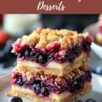 A plate of stacked red, white, and blueberry crumb bars. The crust appears to be made of graham crackers.