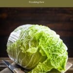 A photo of a head of cabbage on a cutting board next to a knife.