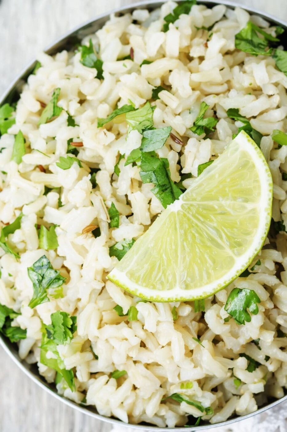  A bowl of fluffy cilantro lime rice garnished with fresh cilantro and lime wedges.