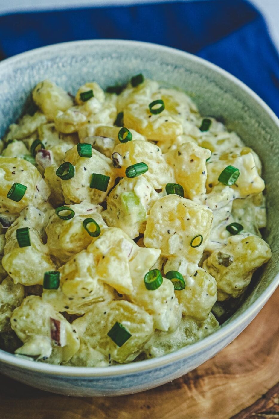 A bowl of creamy Yukon Gold potato salad garnished with fresh herbs and served with a spoon