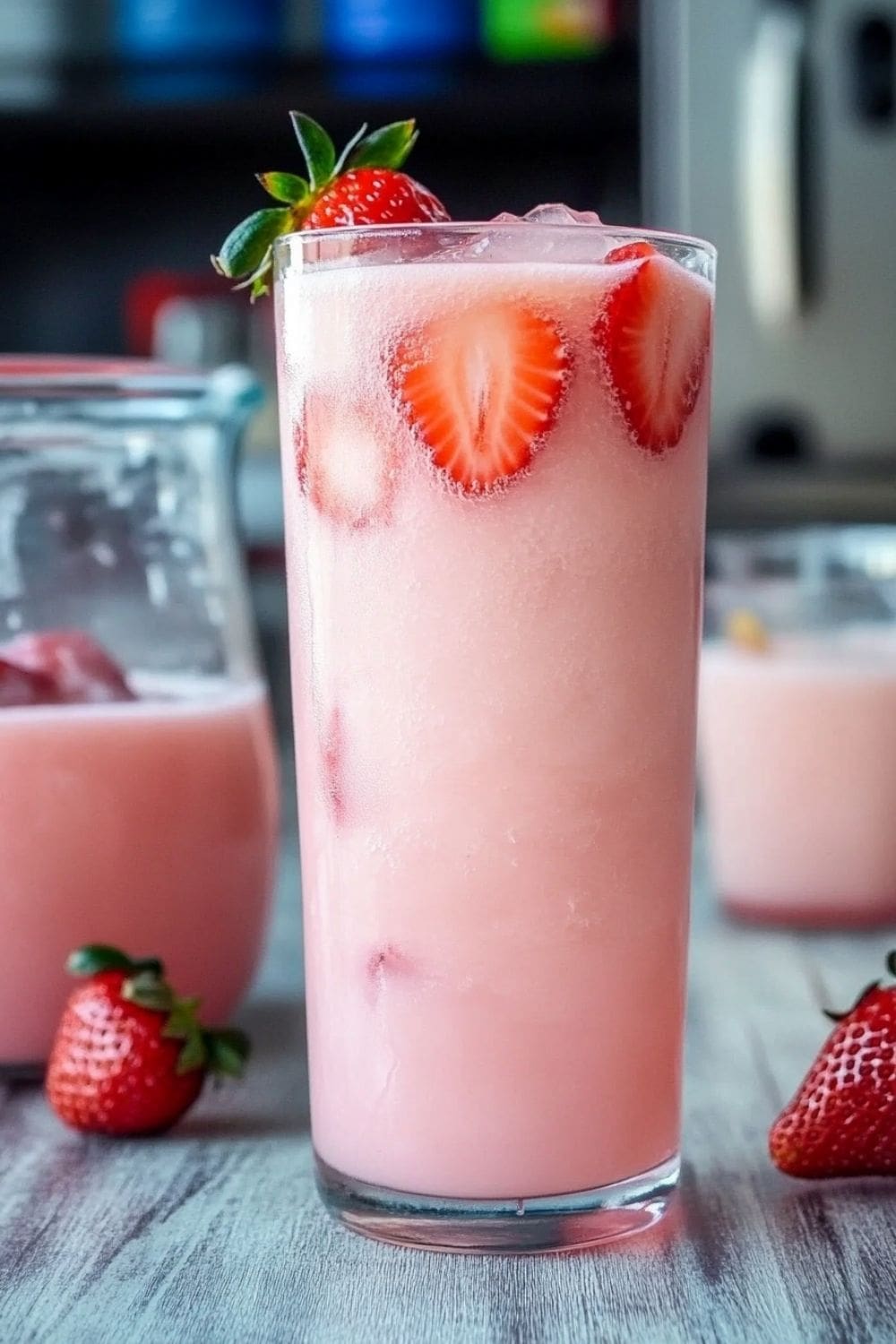 A tall glass of homemade Pink Drink with ice, strawberries, and coconut milk.