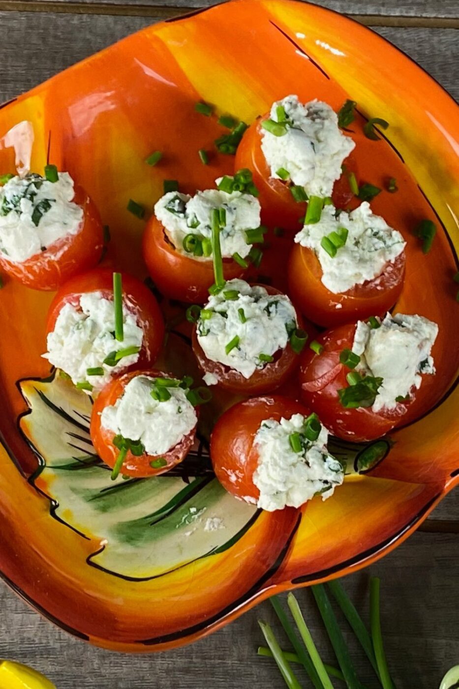 A platter of red cherry tomatoes stuffed with creamy white goat cheese and herbs.