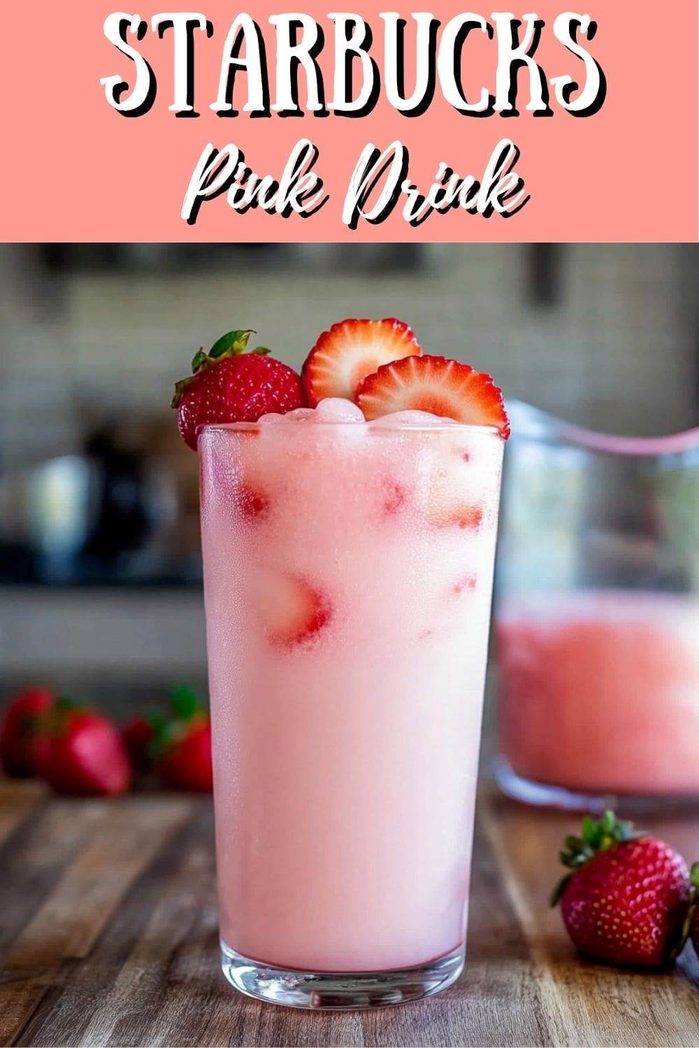 A creamy iced Pink Drink with fresh strawberries on a wooden table.