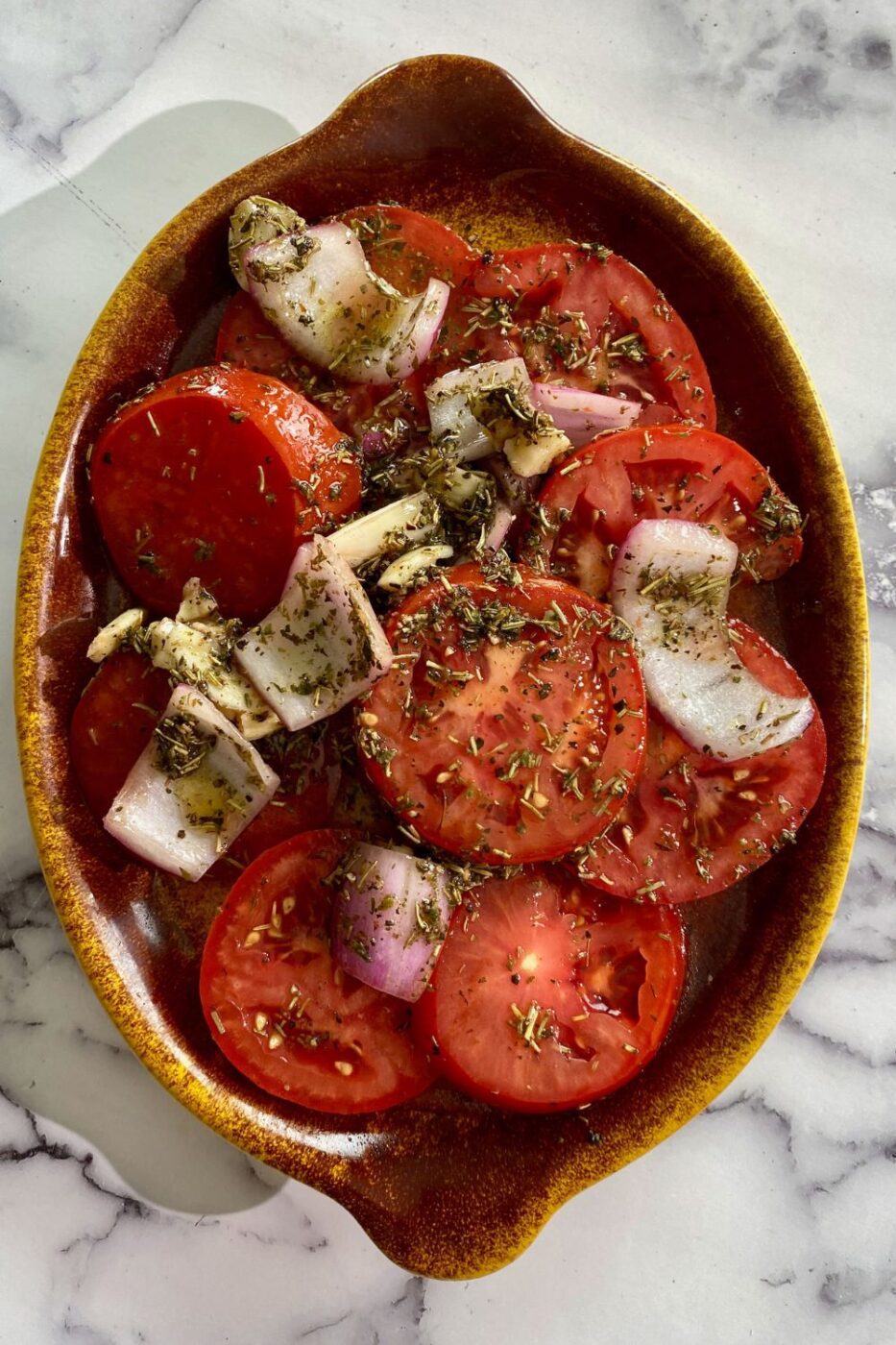 Juicy marinated tomatoes in a garlic herb dressing, served in a bowl with fresh basil.