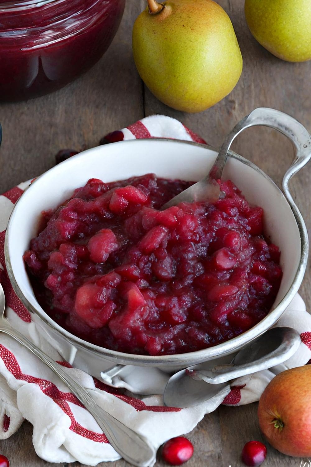 A bowl of cranberry pear sauce sitting on a wooden table. 