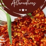 A close-up photo of a pile of crushed red pepper flakes on a light-colored table.