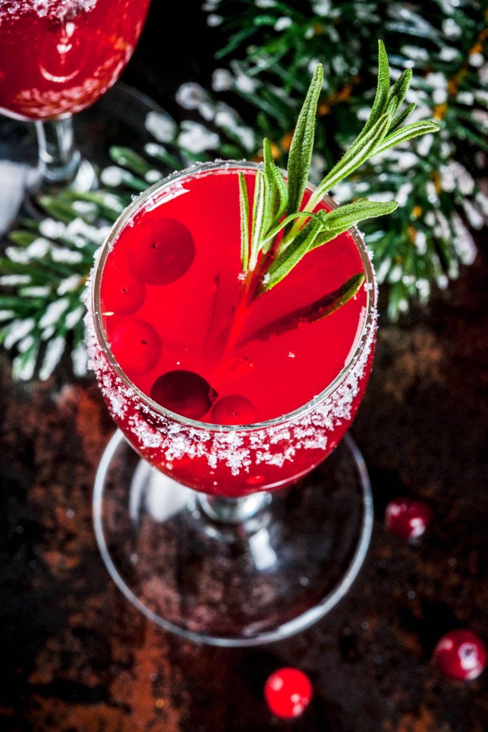 A close-up of a glass filled with Cranberry Prosecco Cocktail, a festive and refreshing drink garnished with fresh cranberries and rosemary. 