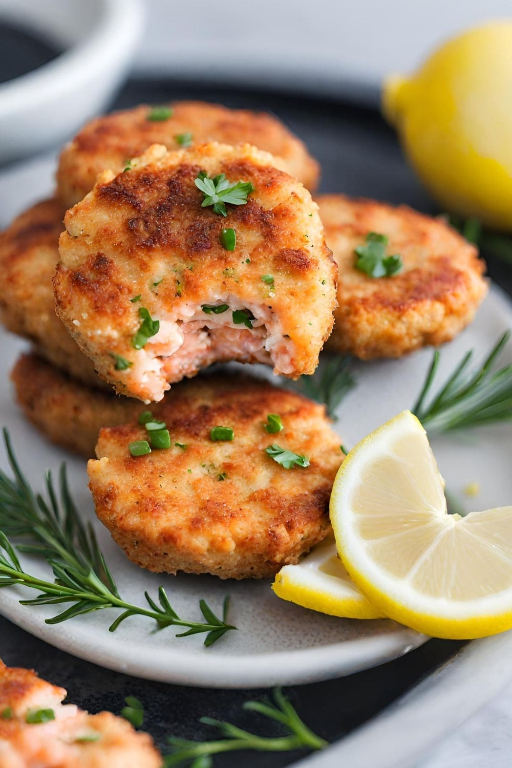 A close-up photo of a plate of mini salmon cakes with a lemon wedge.