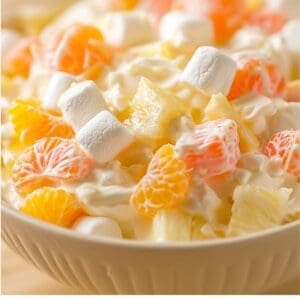 A close-up of a bowl of Hawaiian fruit salad with marshmallows and tropical fruits.