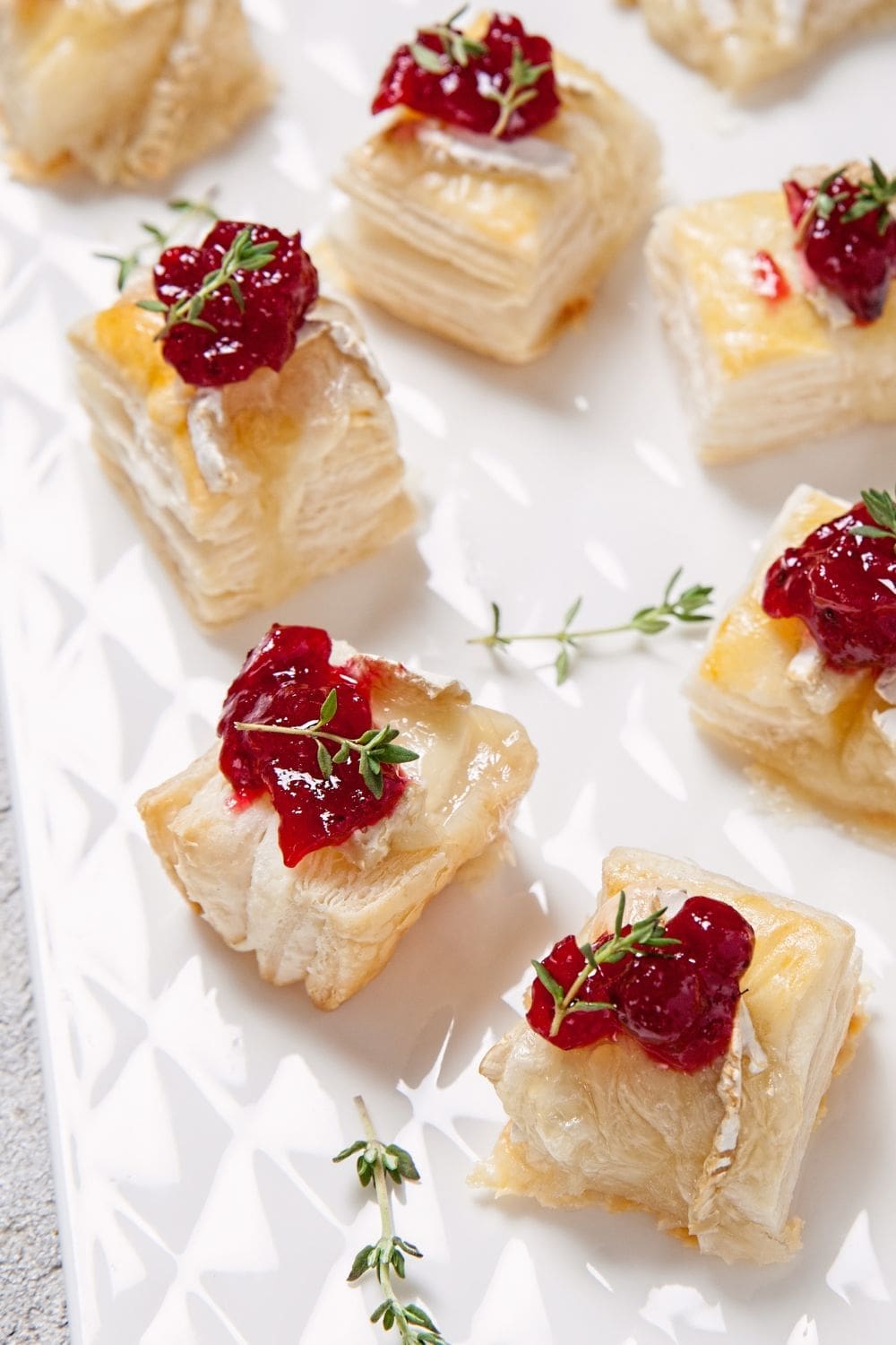 A plate of cranberry brie bites sitting on a white plate.