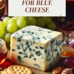 A blue cheese cheeseboard with crackers, grapes, and a glass of wine