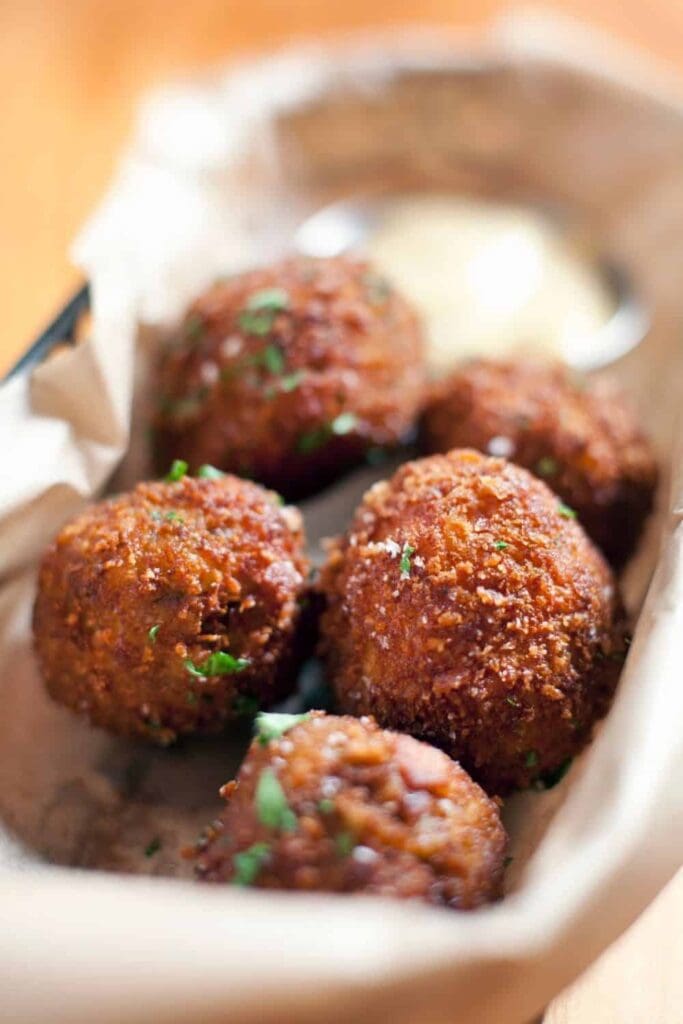 A pile of round hush puppies on a white plate