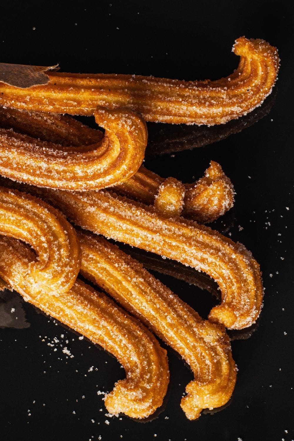 Close-up of crispy churros on a black background.
