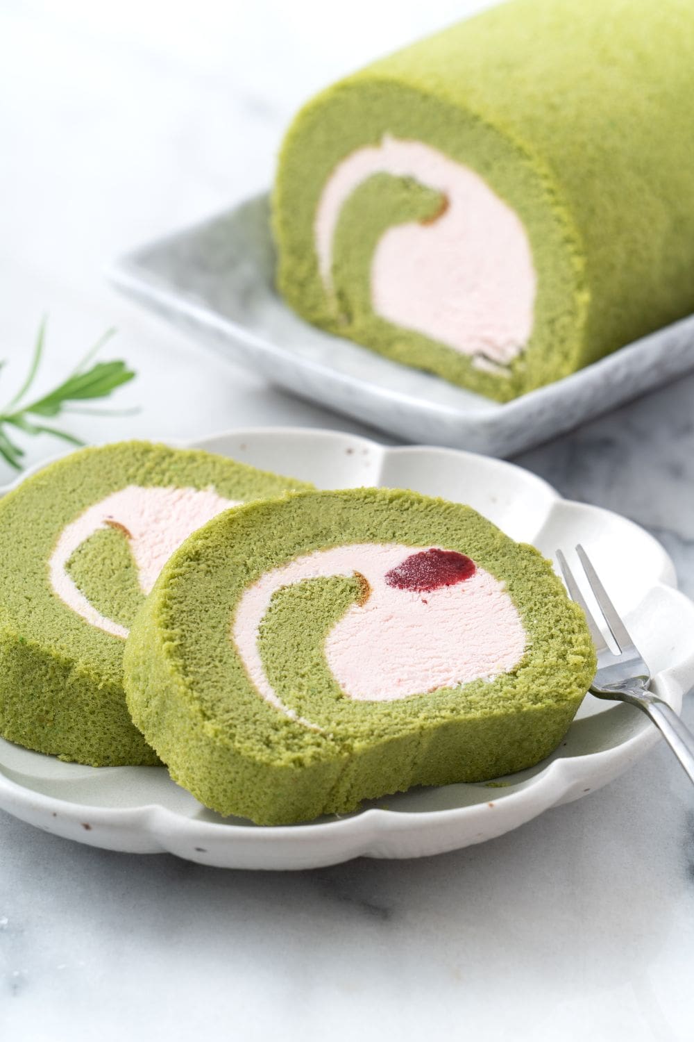 A strawberry matcha roll cake with a light and fluffy sponge cake, fresh strawberries, and whipped cream.