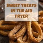 A tray of golden churros dusted with cinnamon sugar, some standing upright and others piled haphazardly, sit bathed in the warm glow of an air fryer's basket.