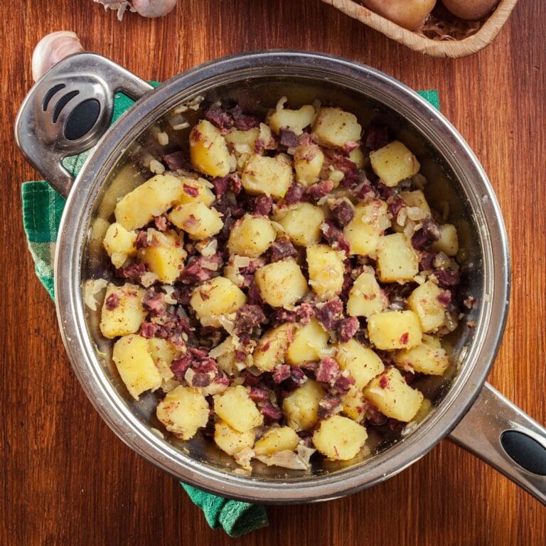 A skillet filled with canned corned beef and cubed potatoes cooked until golden brown.