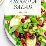 A plate of arugula salad with blue cheese and fruit.